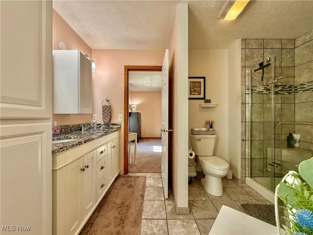 Primary bathroom with double vanity granite counter, stand alone shower, and ceramic floors.