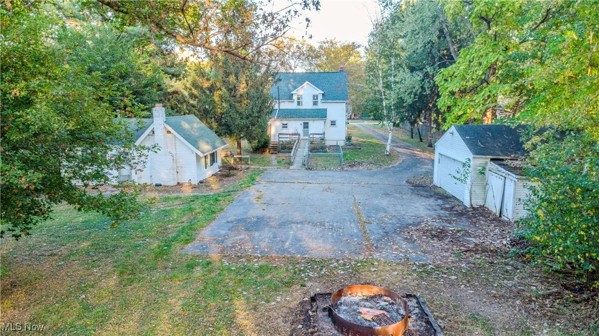 View of yard featuring an outdoor structure, a garage, and a fire pit