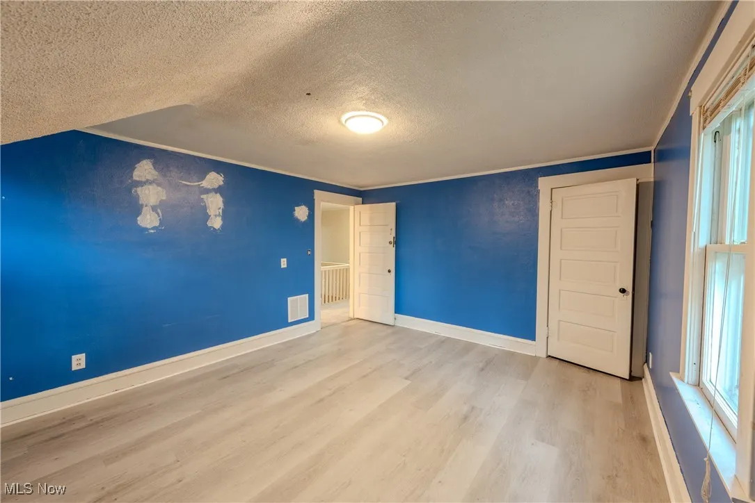 2nd Floor bedroom with vinyle finished floors, a textured ceiling, and ornamental molding