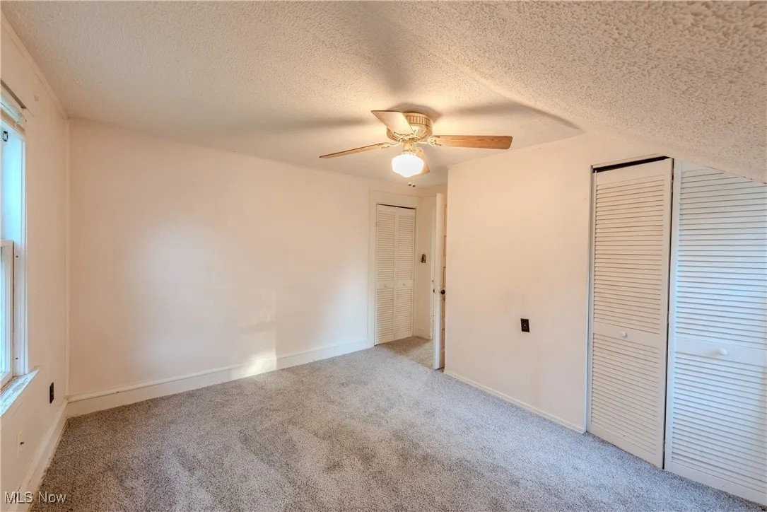 2nd Floor bedroom with a textured ceiling, carpet floors, ceiling fan, and two closets