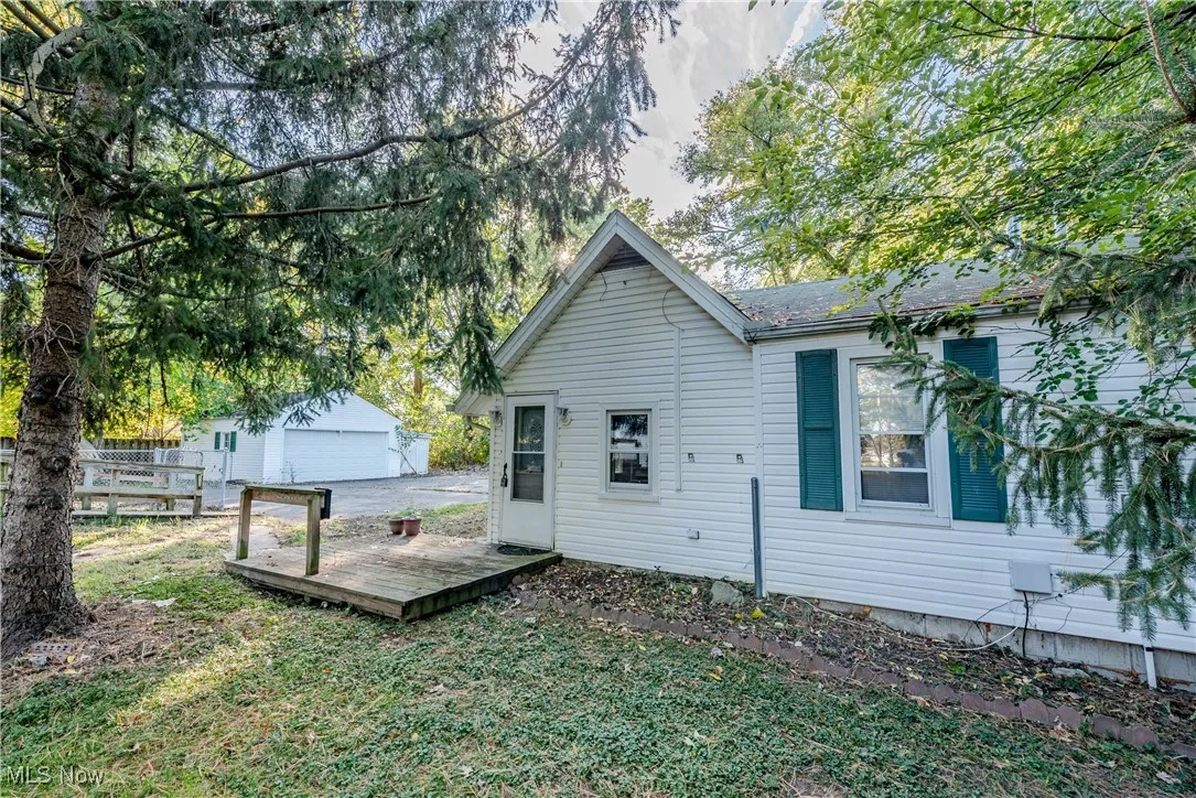 Rear view of house with a wooden deck, an outdoor structure, a yard, and a garage