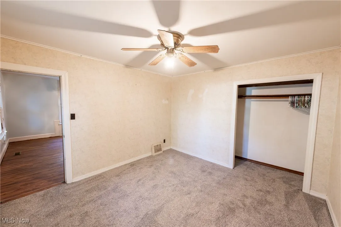 Main Home 1st Fl. bedroom with ornamental molding, carpet floors, a ceiling fan, and a closet
