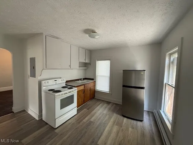 Apartment 4 Kitchen with arched walkways, electric stove, freestanding refrigerator, a baseboard heating unit, and dark wood-style flooring