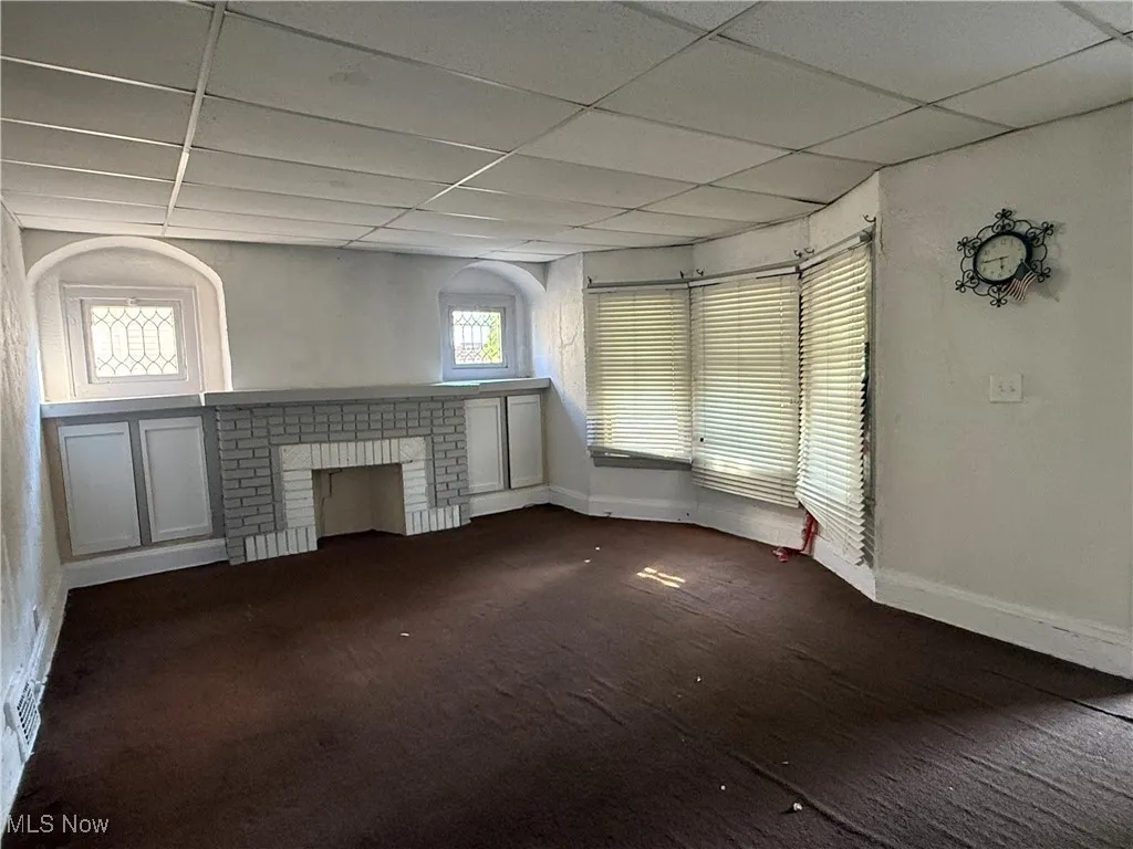 Living room/brick fireplace, carpet, and a paneled ceiling