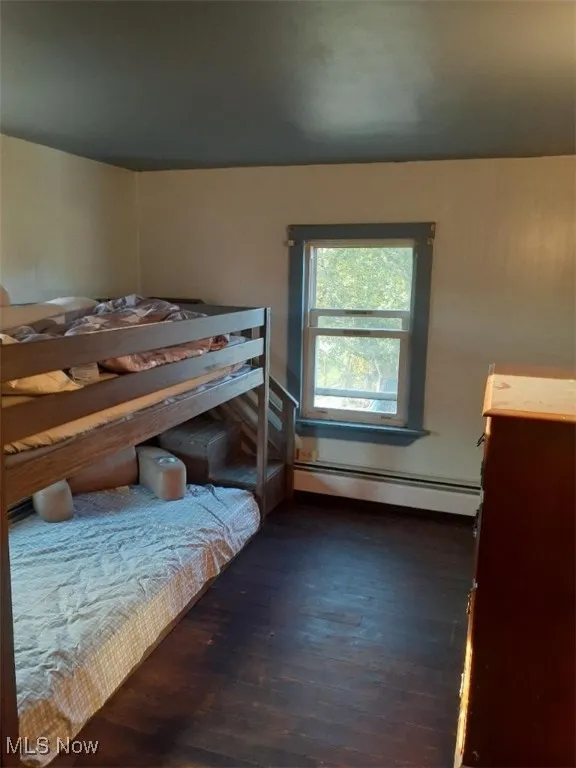 Bedroom with dark wood-style flooring and baseboard heating