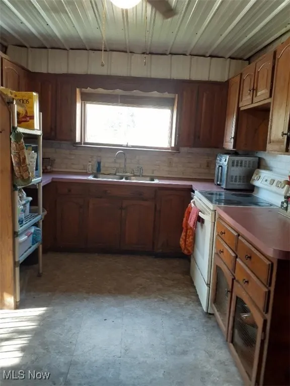 Kitchen featuring electric stove, dark floors, brown cabinets, and light countertops