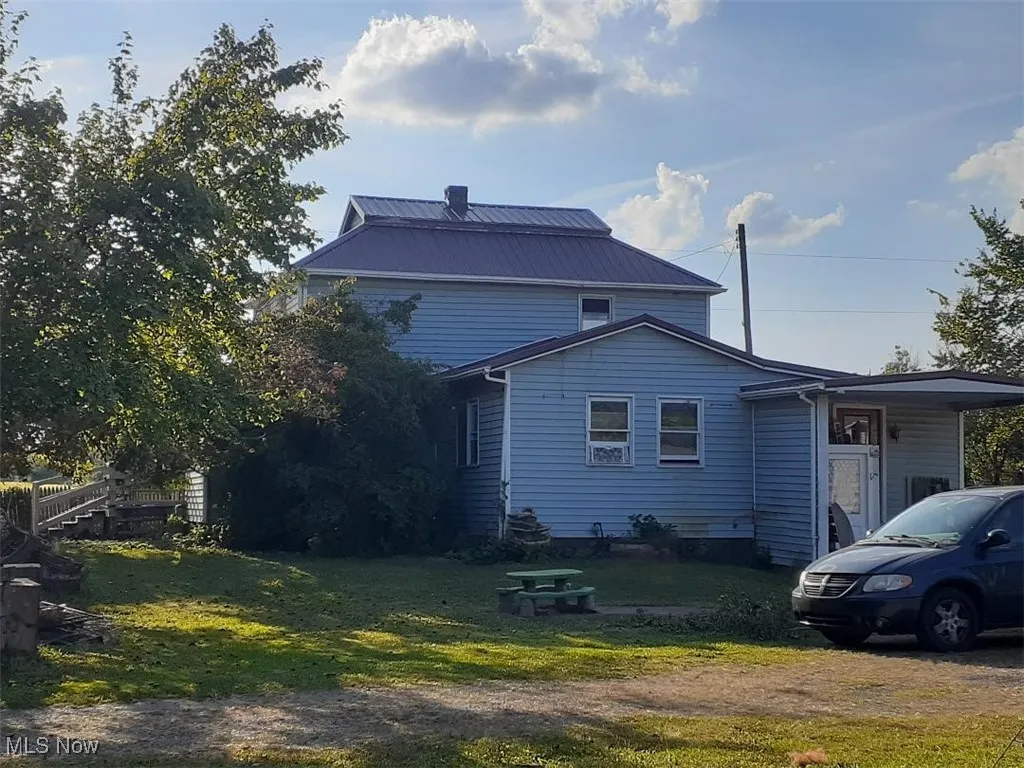 Side of property with a yard, a metal roof, and a chimney