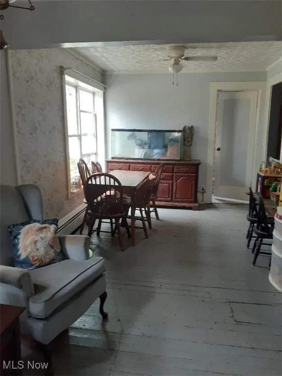 Dining space featuring an ornate ceiling, baseboard heating, and ceiling fan
