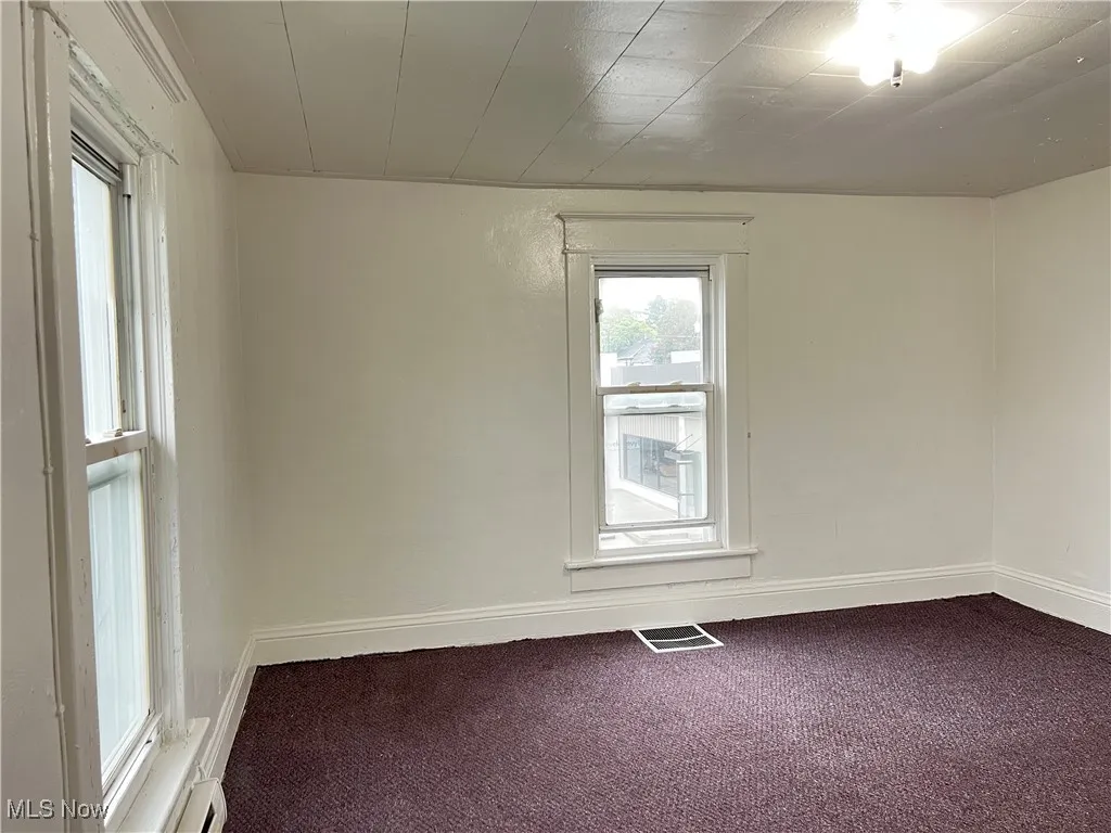 Empty room featuring carpet floors and a baseboard radiator