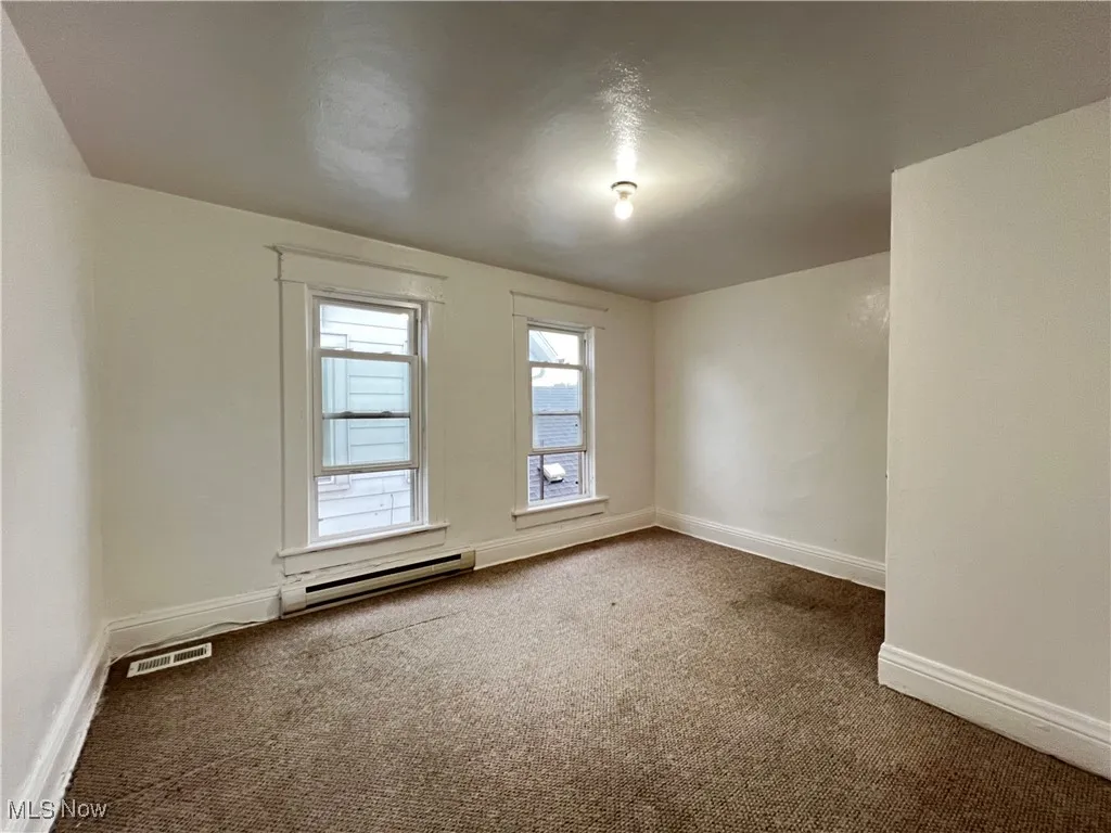 Empty room featuring carpet and baseboard heating