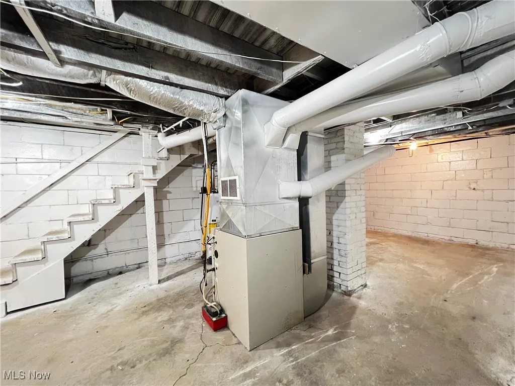 Unfinished below grade area with heating unit and stairway