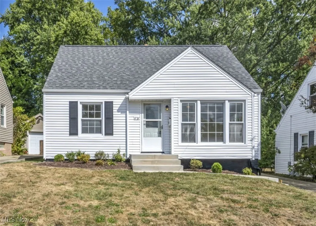 View of front of house with a front yard and roof with shingles