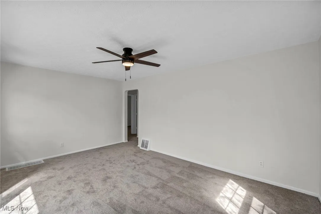 Unfurnished room featuring light colored carpet, ceiling fan, and a textured ceiling