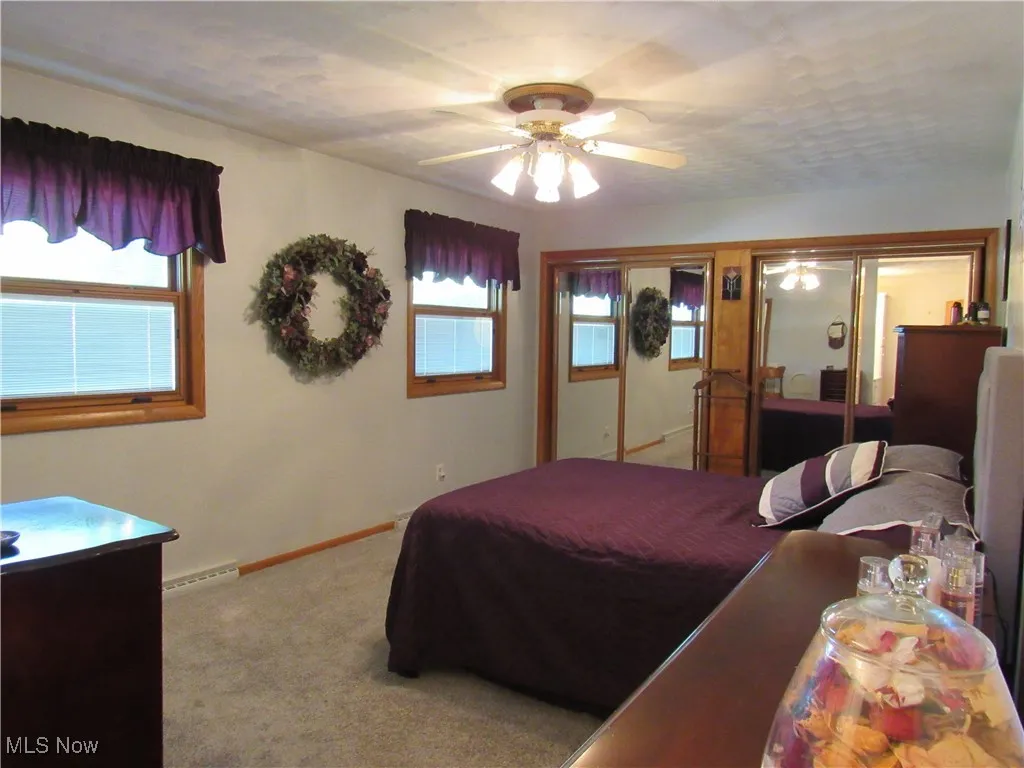 Bedroom with carpet flooring, multiple windows, a ceiling fan