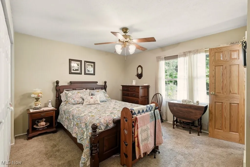 Carpeted bedroom with a ceiling fan and a closet