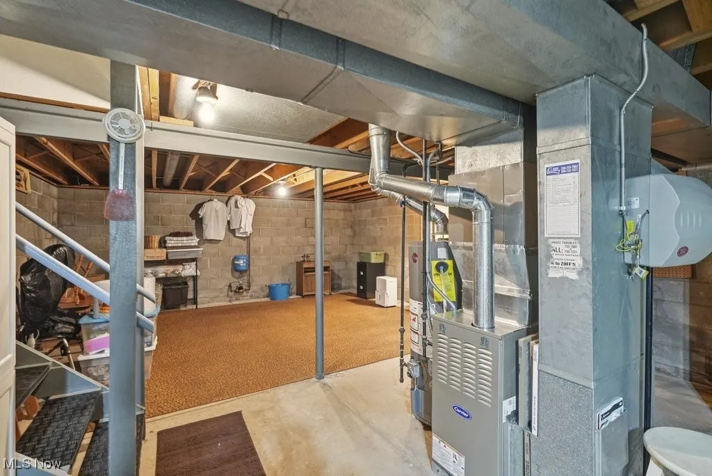Unfinished basement with stairway, water heater, and heating unit