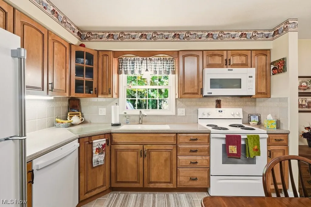 Kitchen featuring white appliances, brown cabinets, and light countertops