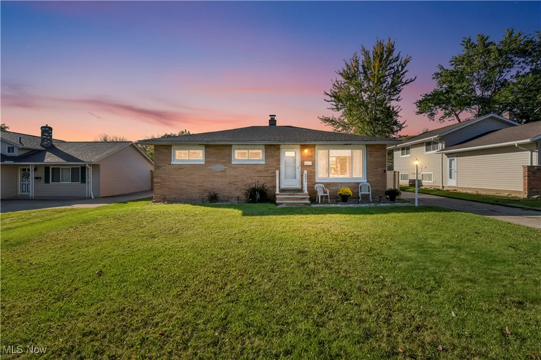 View of front of property with a lawn, a chimney, brick siding, and entry steps