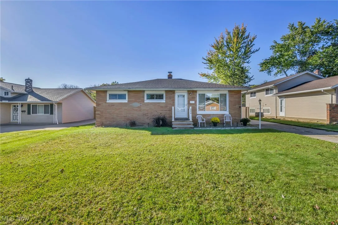 View of front of home with a front lawn, a chimney, brick siding, and entry steps