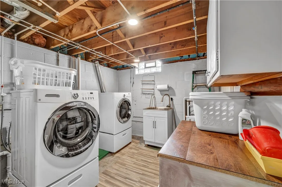 Laundry room with washing machine and dryer, cabinet space, and light wood finished floors