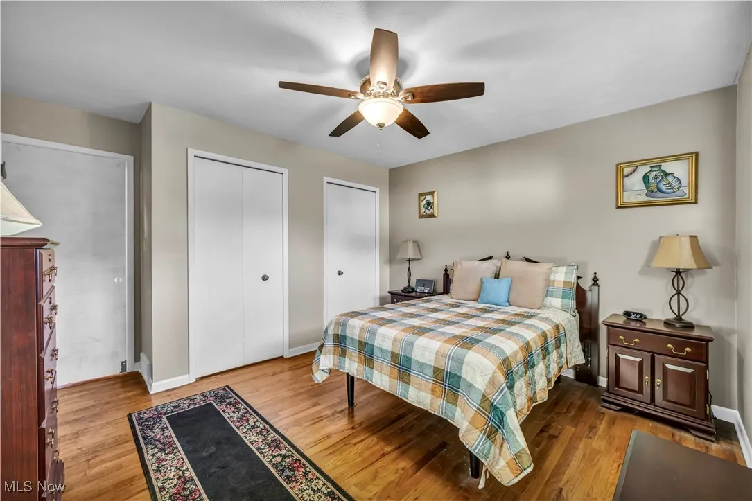 Bedroom featuring two closets, a ceiling fan, and wood finished floors