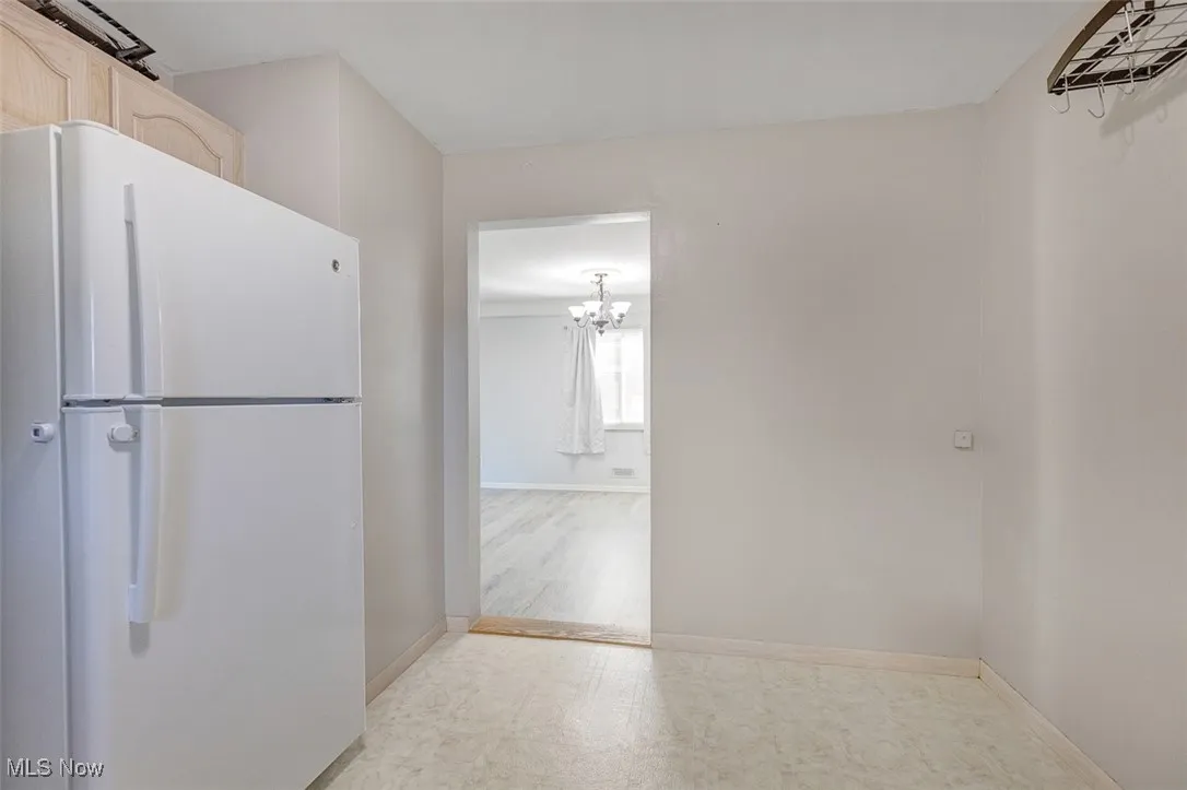 Kitchen featuring freestanding refrigerator, a chandelier, and light flooring