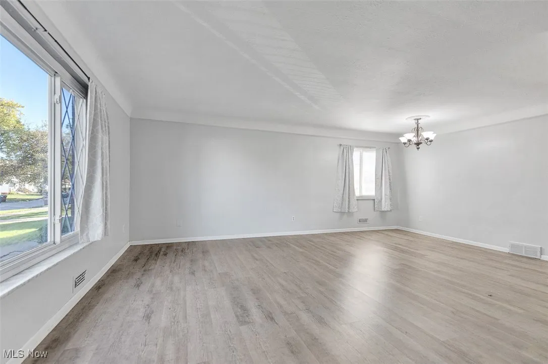 Unfurnished room featuring light wood-type flooring and a chandelier