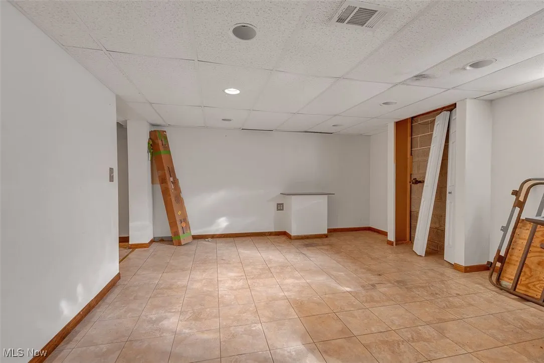 Finished basement with a drop ceiling, light tile patterned floors, and recessed lighting
