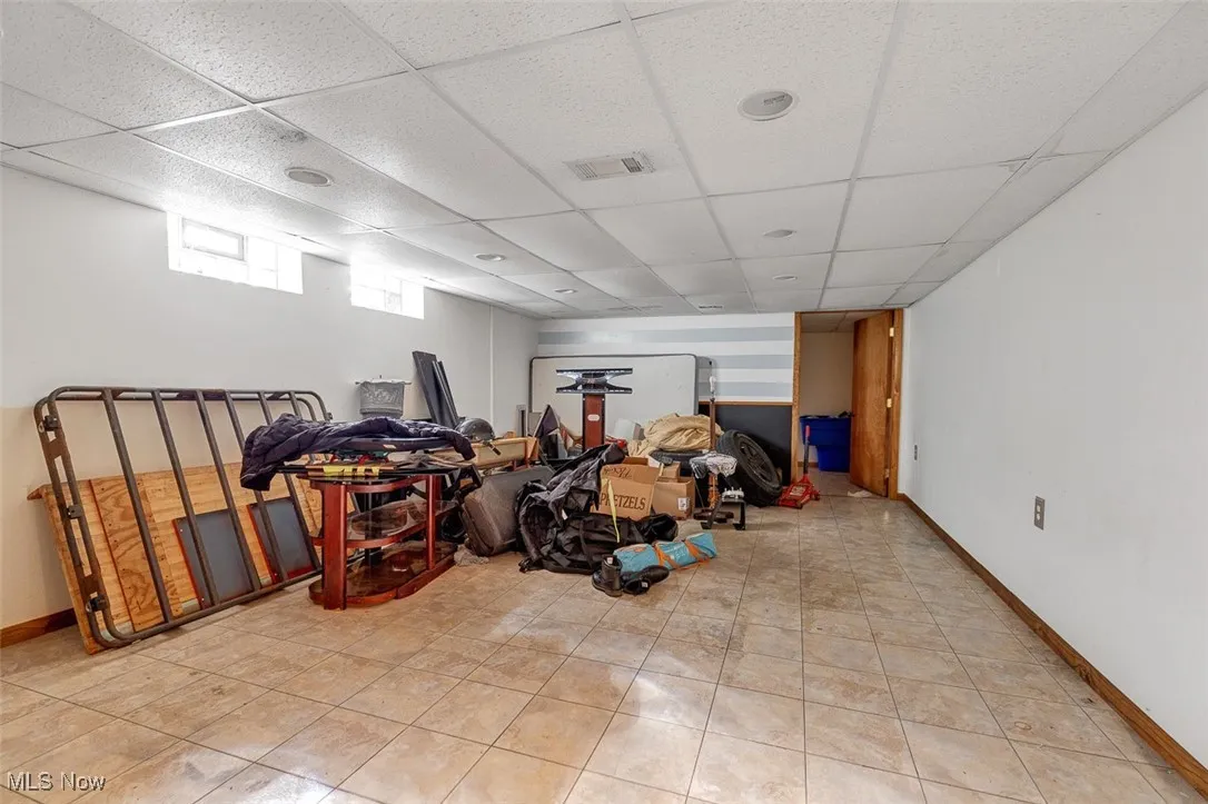Below grade area with a paneled ceiling and light tile patterned flooring