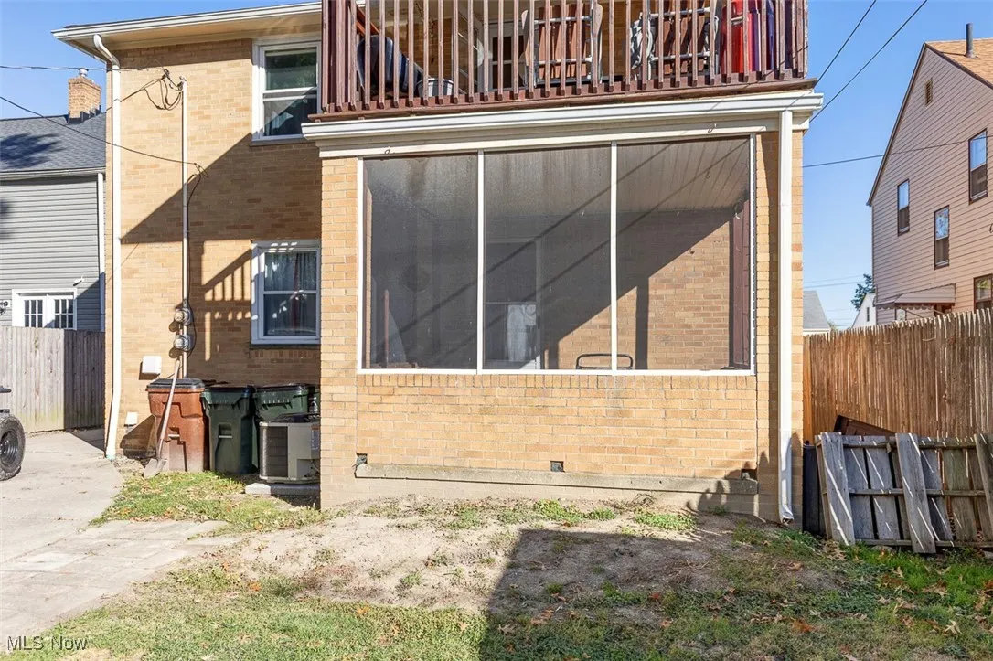 View of side of property with a sunroom, a balcony, and brick siding