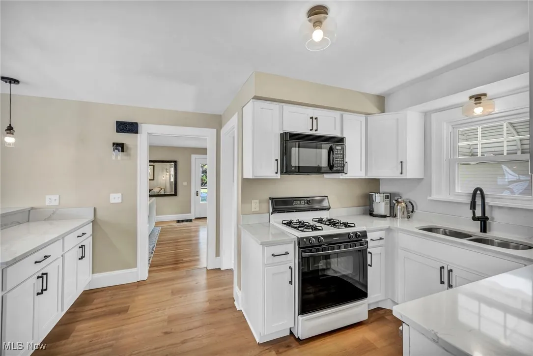 Kitchen featuring gas range, quartz counters, and white cabinets