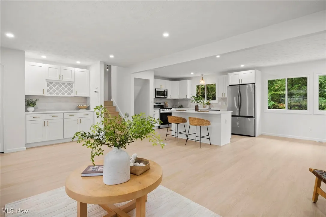 Living room featuring light wood-style floors, recessed lighting, and stairs