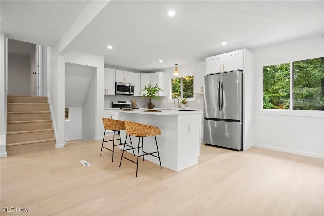 Kitchen featuring stainless steel appliances, backsplash, white cabinets, a kitchen island, and recessed lighting