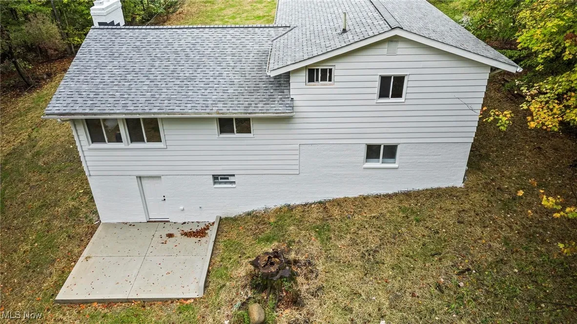 Rear view of house with a chimney, a yard, and a shingled roof