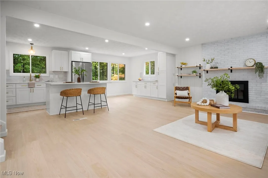 Kitchen featuring white cabinets, a breakfast bar area, a kitchen island, light countertops, and recessed lighting