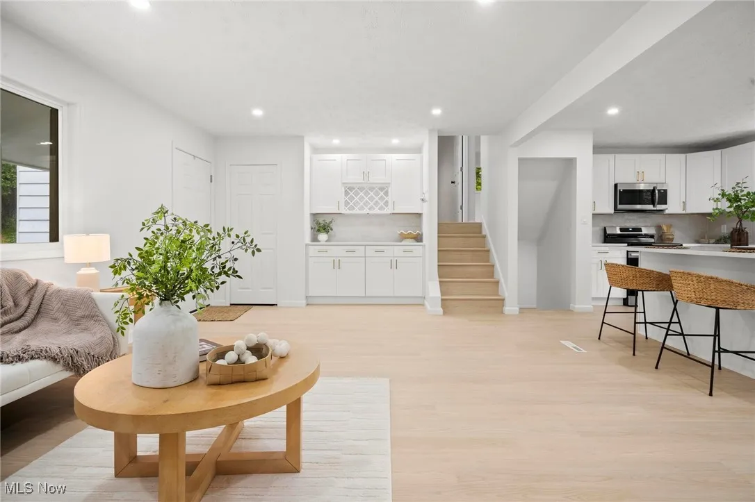 Living room with recessed lighting, light wood-type flooring, and stairs