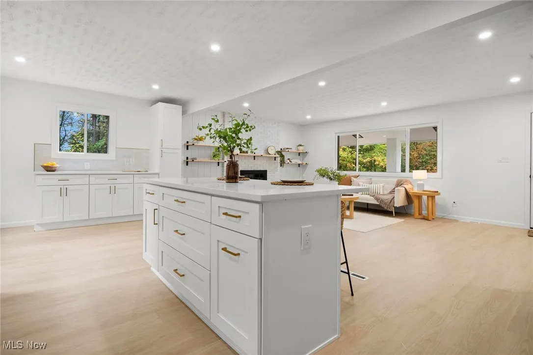 Kitchen with white cabinetry, a breakfast bar, recessed lighting, a kitchen island, and light wood finished floors