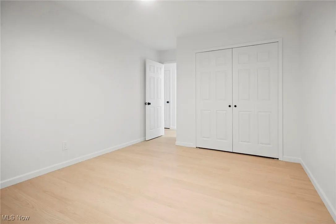 Unfurnished bedroom featuring light wood-style floors and a closet