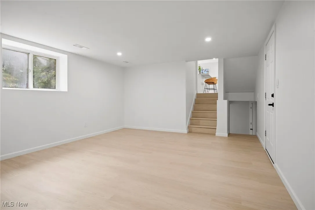 Basement with stairs, light wood-style flooring, and recessed lighting