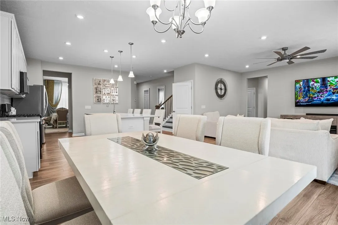 Dining room featuring light wood finished floors, recessed lighting, ceiling fan, stairs, and a chandelier