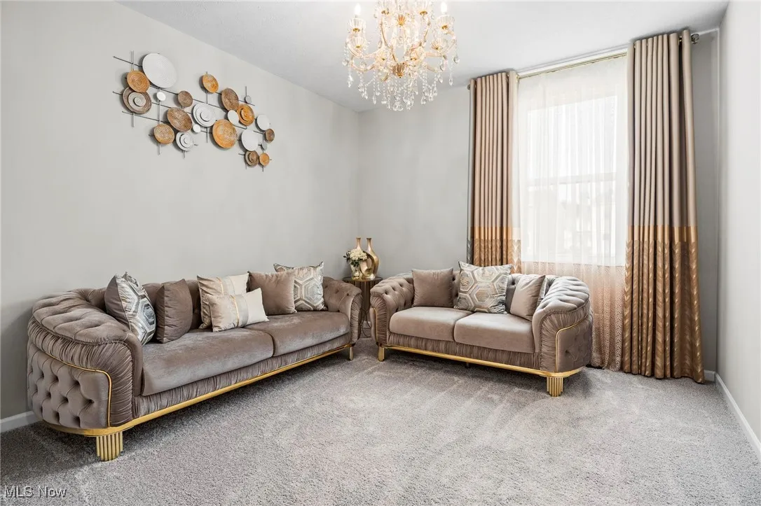 Carpeted living room with a chandelier and baseboards