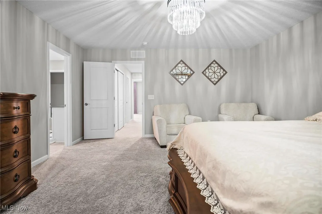 Bedroom with a chandelier and light carpet