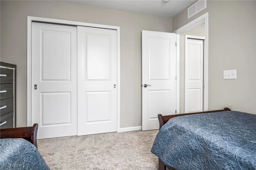 Carpeted bedroom with a closet and a textured ceiling
