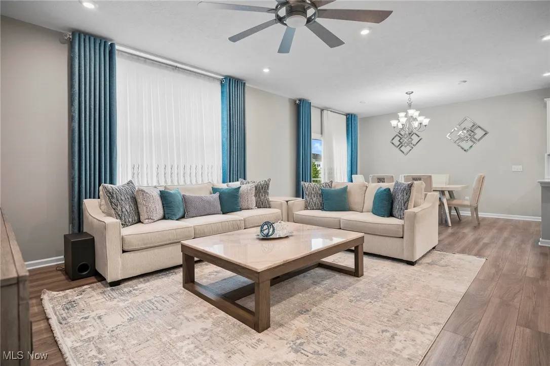 Living room with wood finished floors, recessed lighting, a chandelier, and a ceiling fan