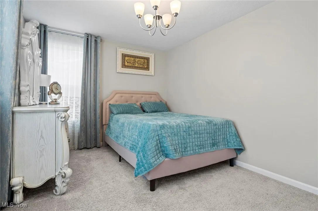 Carpeted bedroom featuring a chandelier and baseboards