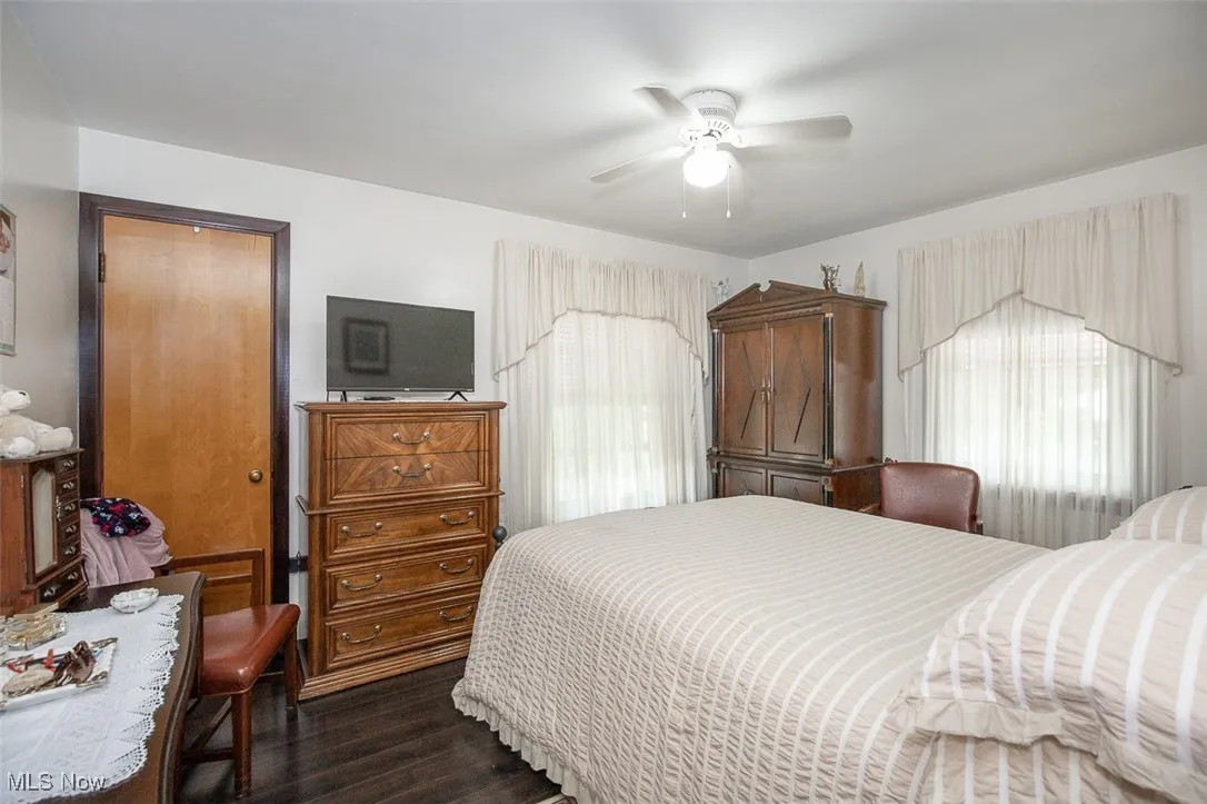 First floor bedroom with wood flooring, multiple windows, and ceiling fan.