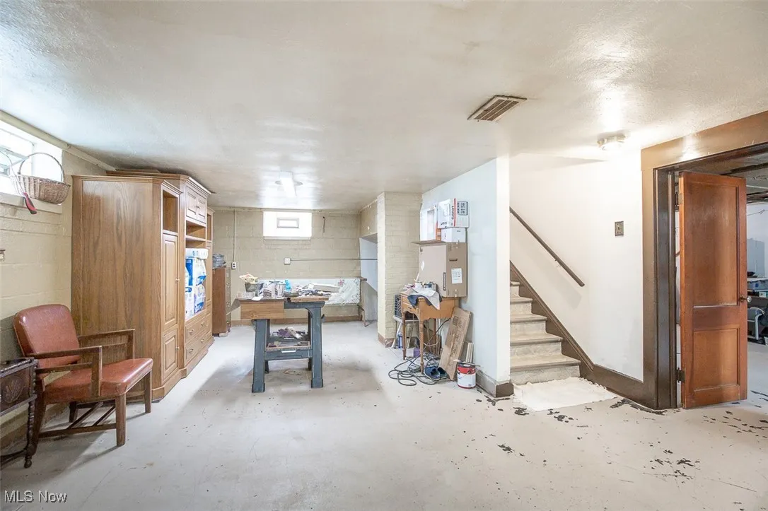 Basement with a textured ceiling, concrete block wall, and glass block windows.