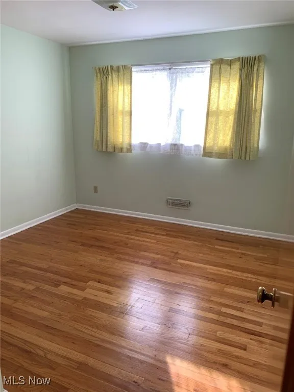 Empty room with baseboards and wood-type flooring