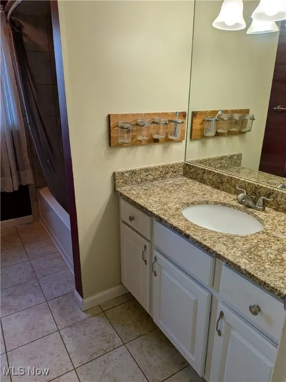 Full bathroom featuring vanity, shower / bath combination with curtain, and light tile patterned flooring