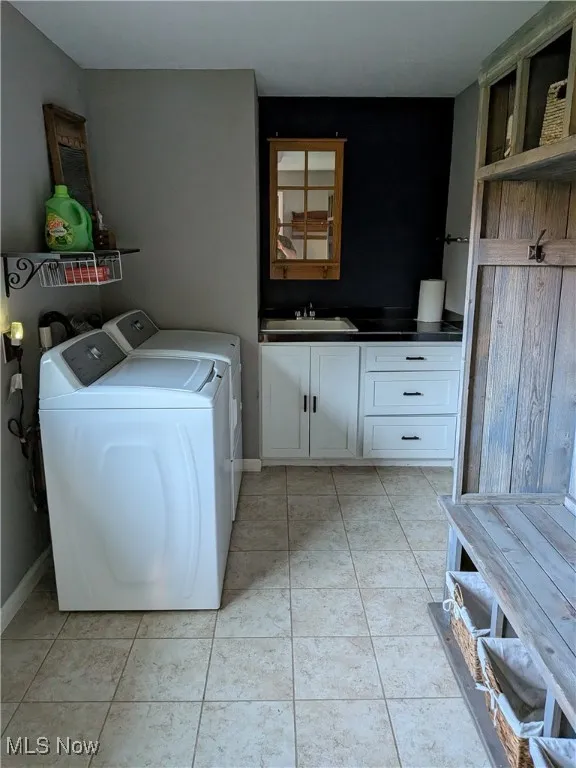 Laundry area featuring light tile patterned floors, washer and clothes dryer, and cabinet space
